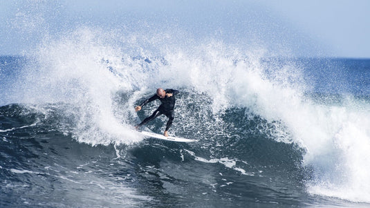 Surfer wearing a Billabong Absolute Wetsuit on the lip of wave.