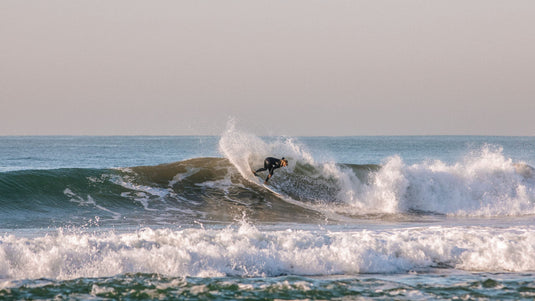Surfer wearing a women's cold water wetsuit surfing in the ocean.